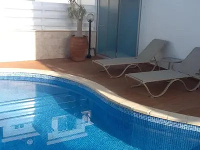 a swimming pool with two lounge chairs and a table at Fig Tree Bay Villa Elena in Protaras