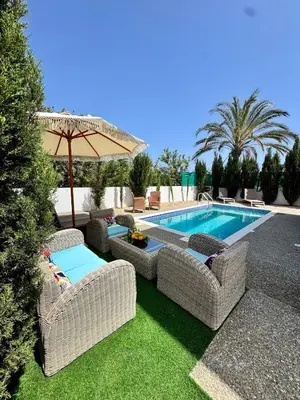 a swimming pool with wicker chairs and an umbrella at Villa Jarvis Modern and Quiet 3BR with Private Swimming Pool in Paralimni