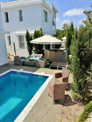 a swimming pool with chairs and an umbrella next to a house at Villa Jarvis Modern and Quiet 3BR with Private Swimming Pool in Paralimni