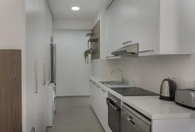 a white kitchen with a sink and a refrigerator at Seabreeze Residence by Staycom in Larnaka