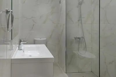 a white bathroom with a shower and a sink at Seabreeze Residence by Staycom in Larnaka