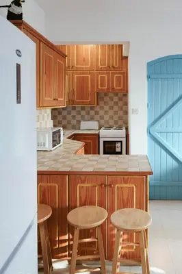 a kitchen with wooden cabinets and stools in it at L'Azure 24 - Protaras in Paralimni