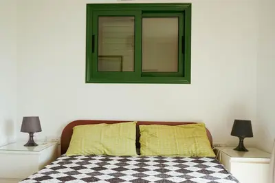a bed with a green window and two night stands at Mediterraneo 27 - Protaras in Protaras