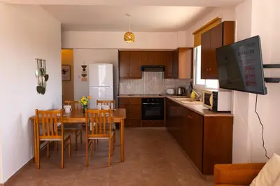 a kitchen with a table and chairs and a refrigerator at STAY Kali Sun Apartment in Paralimni