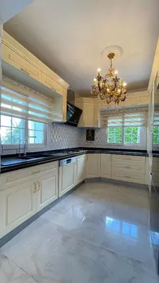 a large kitchen with white cabinets and a chandelier at Kingdom Villa with Sauna and Hamam in Kaimakli