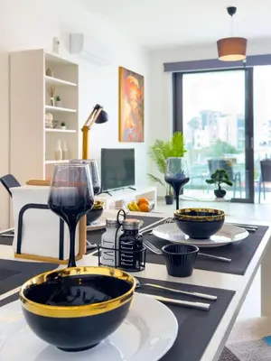 a table with plates and wine glasses on it at Sunset Balcony and Espresso Station Apartment in Larnaka
