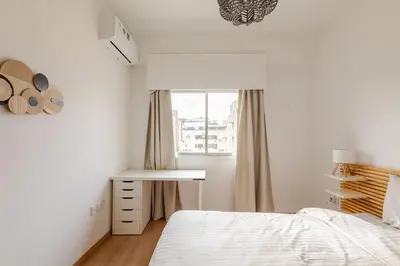 a white bedroom with a bed and a window at Cosy 2-Bedroom Apartment, 10 Minutes from the Beach in Larnaka