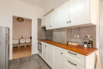 a kitchen with white cabinets and a dining room at Cosy 2-Bedroom Apartment, 10 Minutes from the Beach in Larnaka