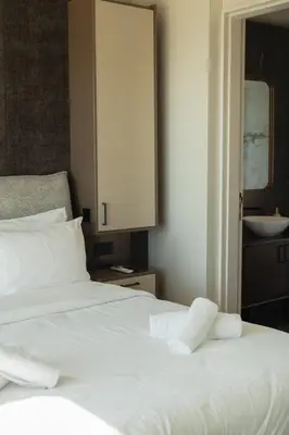 a white bed with two pillows and a cabinet at Infinity Residences in Zygi