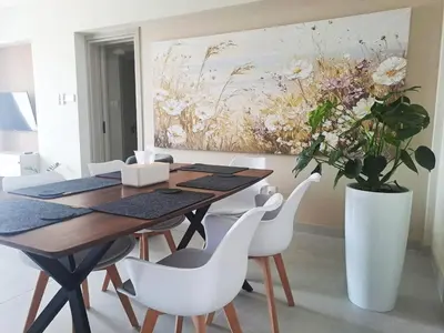 a dining room with a table and chairs and a painting at Sea View Floral Suite - 2 bedroom in Larnaka