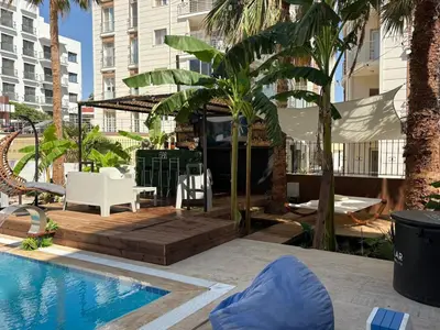 a pool in a hotel with chairs and palm trees at Heritage Villas Northern Cyprus in Mağusa