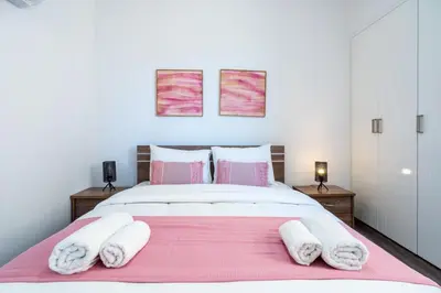 a bedroom with a large bed with pink and white pillows at Olympus Stylish 2-BR Apt & Balcony in Larnaca in Larnaka