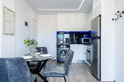 a kitchen with a table and chairs and a refrigerator at Olympus Stylish 2-BR Apt & Balcony in Larnaca in Larnaka
