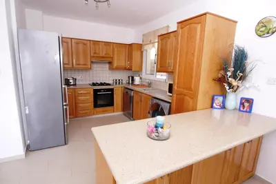 a kitchen with wooden cabinets and a stainless steel refrigerator at Maouris Villa in Protaras