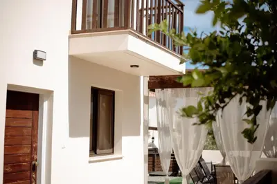 a white house with a balcony with curtains at Villa Lela in Paralimni
