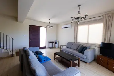 a living room with two blue couches and a tv at Maestro Villa II - Pervolia in Pervolia