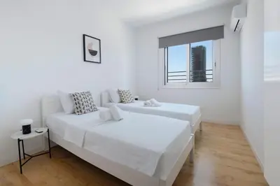 two beds in a white room with a window at Urban Condo 10th Floor - 2 Bdr in Nicosia
