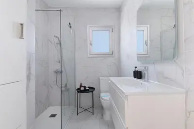 a white bathroom with a sink and a shower at Urban Condo 10th Floor - 2 Bdr in Nicosia