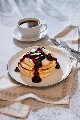 a plate of pancakes with berries and a cup of coffee at Urban Condo 10th Floor - 2 Bdr in Nicosia