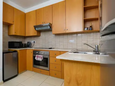 a kitchen with wooden cabinets and a sink at City Center Flat 23 in Larnaka