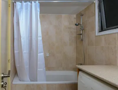 a bathroom with a shower with a white shower curtain at City Center Flat 23 in Larnaka