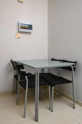 a glass table with two black chairs around it at City Center Flat 23 in Larnaka