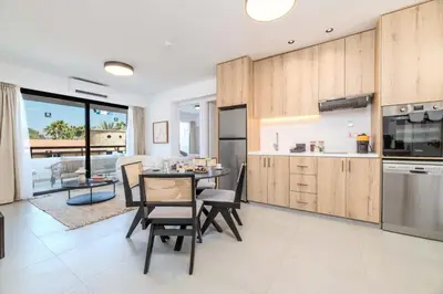 a kitchen with wooden cabinets and a table and chairs at Finikoudes Marina View 102 in Larnaka