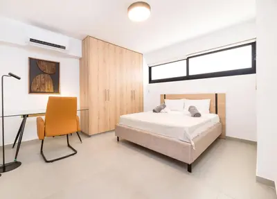 a bedroom with a bed and a desk and a chair at Finikoudes Marina View 102 in Larnaka