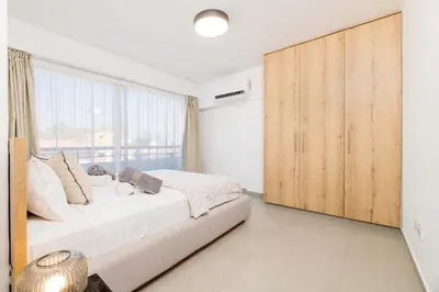 a bedroom with a bed and a large window at Finikoudes Marina View 102 in Larnaka