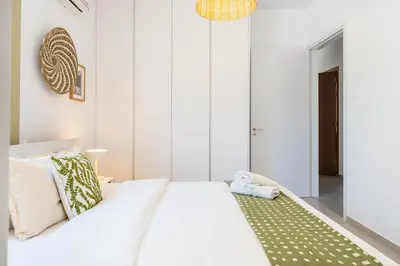 a bedroom with a white bed with a green rug at Solenne - Stylish 2-BR Apartment & Balcony in Larnaca in Larnaka