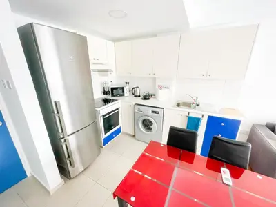a kitchen with a red table and a refrigerator at Awaken Your Hidden Goddess Retreat at Nissi Avenue - Central Ayia Napa in Ayia Napa