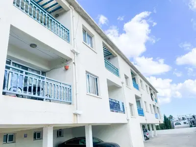 a white building with blue balconies and a car parked outside at Awaken Your Divine Self Sacred Self Discovery Retreat in Ayia Napa Cyprus in Ayia Napa