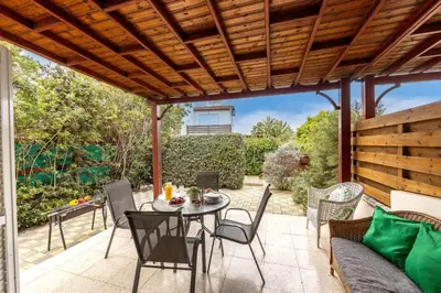 a patio with a table and chairs under a wooden pergola at Larnaca Seaside Villa Marina 43 in Pervolia
