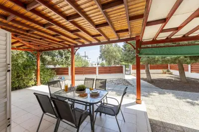 a patio with a table and chairs under a wooden pergola at Larnaca Seaside Villa Marina 44 in Pervolia