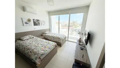 a bedroom with two beds and a tv and a window at Bow Villa in Paralimni