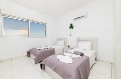 two beds in a white room with a window at Elite Blu Heights Villa in Ayia Napa