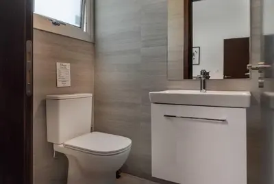 a bathroom with a toilet and a sink and a mirror at Phaedrus Living Travertine Residences 101 in Strovolos