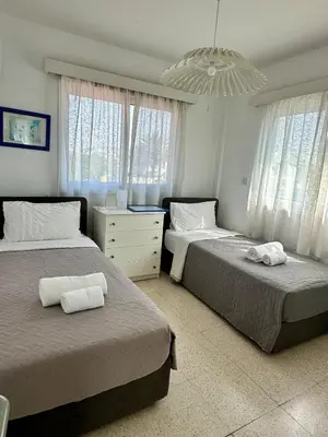 a bedroom with two beds and a chandelier at Sunrise Maisonette in Voroklini