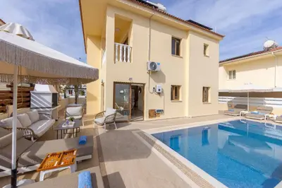 a villa with a swimming pool next to a building at Villa Poseidon in Paralimni