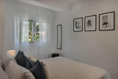a white bedroom with a bed and three pictures on the wall at Phaedrus Living Travertine Residences 102 in Strovolos