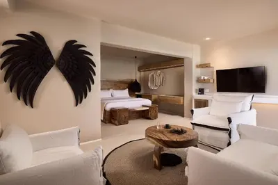a room with two beds and a living room with white furniture at Aya Resort - Adults Only in Ayia Napa