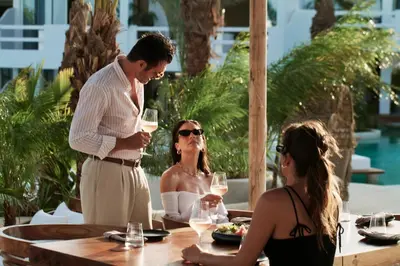 a man and two women sitting at a table with wine glasses at Aya Resort - Adults Only in Ayia Napa