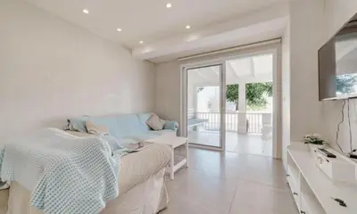 a white living room with a couch and a window at Deluxe Apt - 500m Nissi Beach! in Ayia Napa