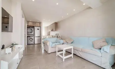 a living room with a blue couch and a kitchen at Deluxe Apt - 500m Nissi Beach! in Ayia Napa