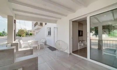 a white house with a patio with a table and chairs at Deluxe Apt - 500m Nissi Beach! in Ayia Napa