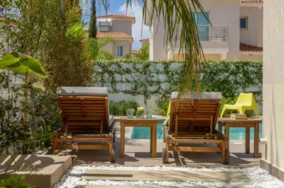 a patio with two chairs and a table and a fence at Protaras El Sol Villa in Protaras