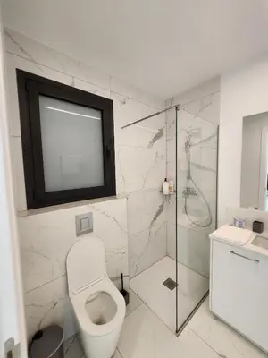 a bathroom with a toilet and a glass shower at Infinity Luxury Mansions in Yeri