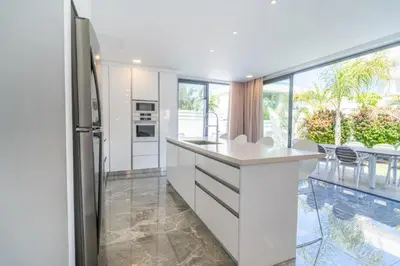 a white kitchen with a refrigerator and a table at Panorama Luxury Summer Villa in Protaras