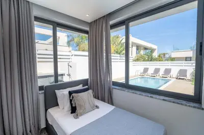 a bedroom with a bed and a large window with a pool at Panorama Luxury Summer Villa in Protaras