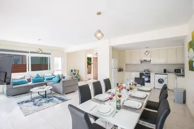 a dining room and living room with a table and chairs at Protaras Mesogeios Villa Me16 Beachfront Villa in Protaras Center in Protaras